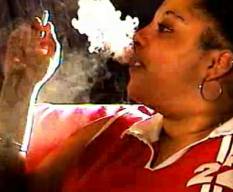 Black girl sits and puffs in a cloud of smoke
